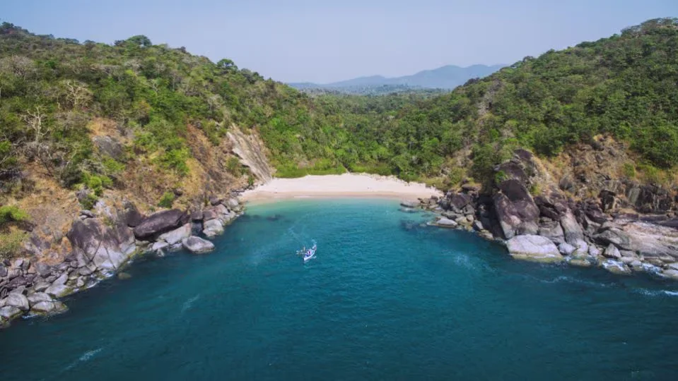 Beautiful high-angle drone photograph of the secluded Butterfly Beach cove nestled between green hills