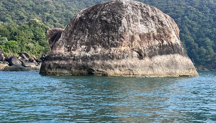 Scenic view from a boat showing a giant dome shaped rock rising from the sea near Butterfly Beach