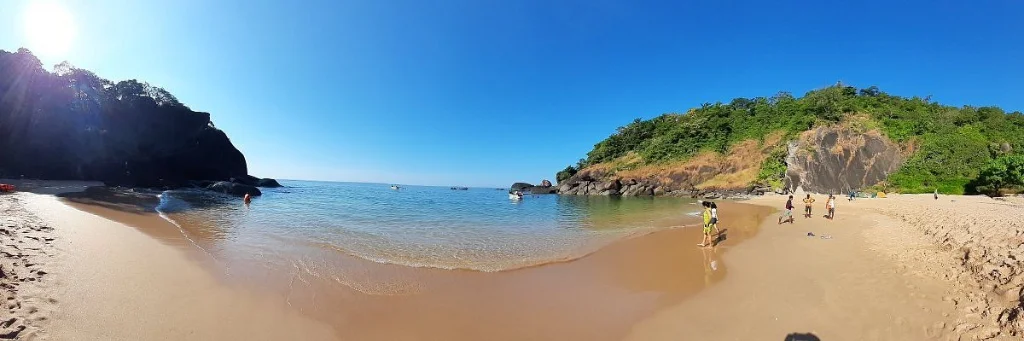 Crescent shaped golden sand cove of Butterfly Beach under a bright sunny blue sky