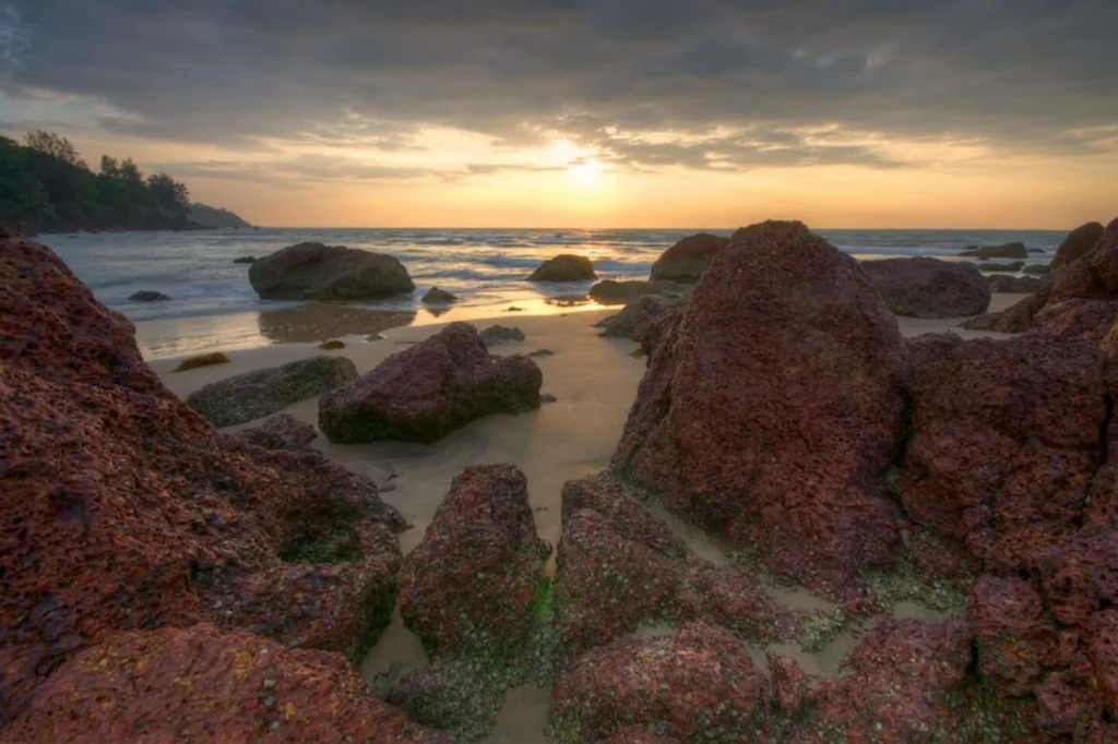 Red volcanic rocks along the tide line at Galgibaga Beach during sunset