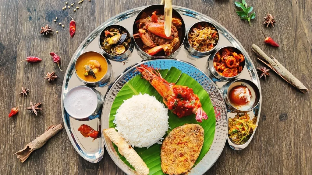 A traditional luxury Goan brass thali featuring lobster, curries, and rice